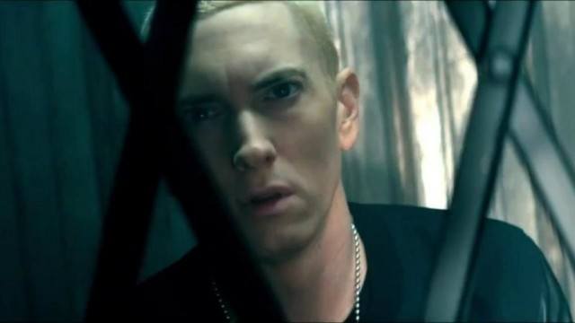 Eminem looks at the camera behind a gate.