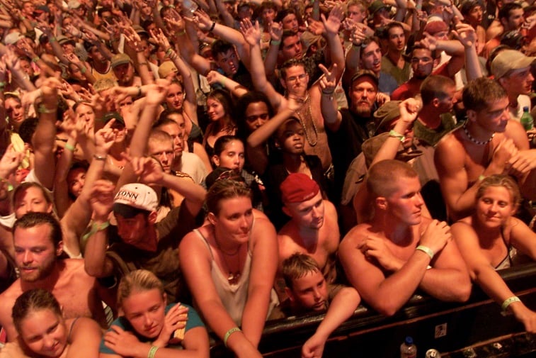 The concert goers are waving their arms in the air.
