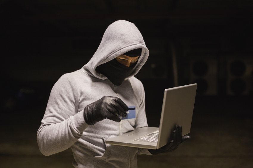 Hacker with credit card and laptop