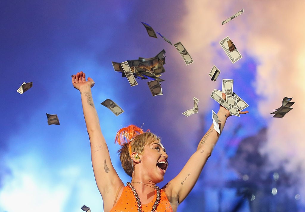 Miley Cyrus throwing money in the air on stage.