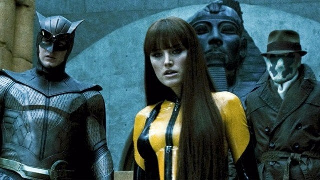Patrick Wilson as Nite Owl, Malin Akerman as Silk Spectre, and Jackie Earle Haley as Rorschach dressed in costume in front of an Egyptian statue in Watchmen