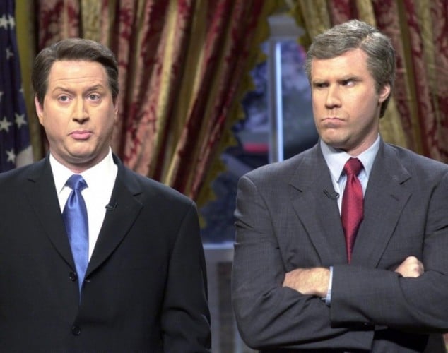 Will Ferrel in a suit and red tie looks over at his co-star while crossing his arms.