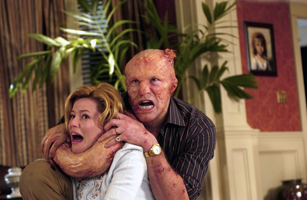 Elizabeth Banks in a living room being attacked by a grotesque transforming Michael Rooker in Slither