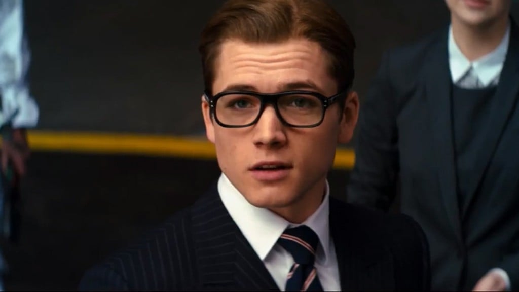 Taron Egerton wearing suits and glasses in Kingsman. 