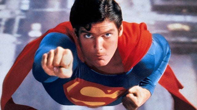 Christopher Reeve with his arm extended, flying through the air as Superman