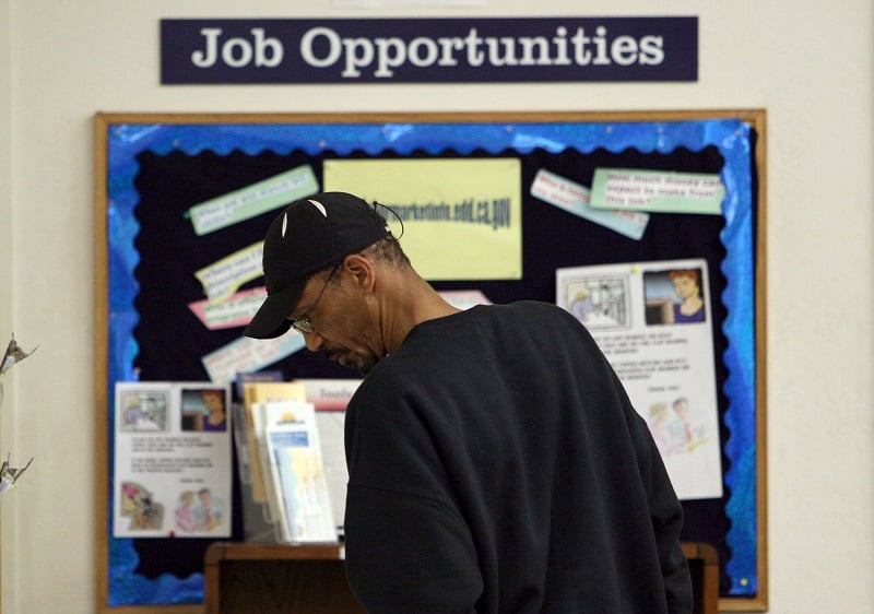 A man stands in front of a job board