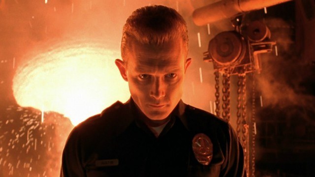 T-1000 is dressed as a policeman and is standing in front of fire.