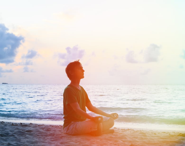 Silhouette of young man meditating at sunset beach Silhouette of young man meditating at sunset beach