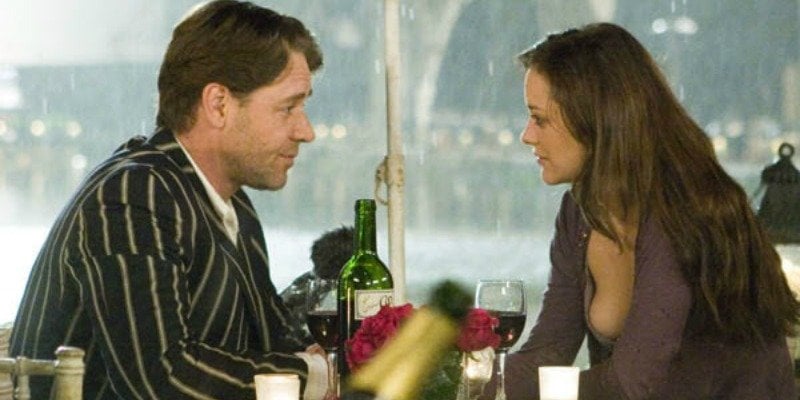 Russell Crowe and Marion Cotillard look at each other over a bottle of wine and glasses