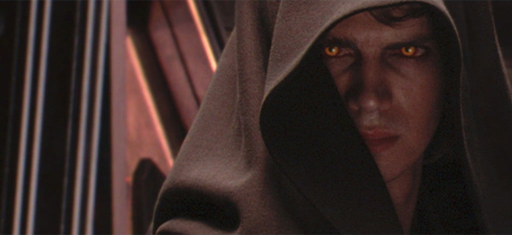Anakin Skywalker, with yellow eyes and a brown hood, looking angrily off into the distance