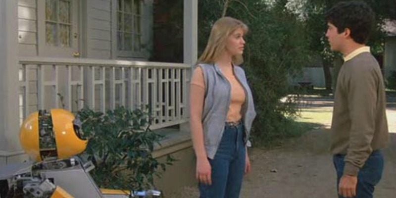 A young man and woman talk as a robot watches in Deadly Friend.