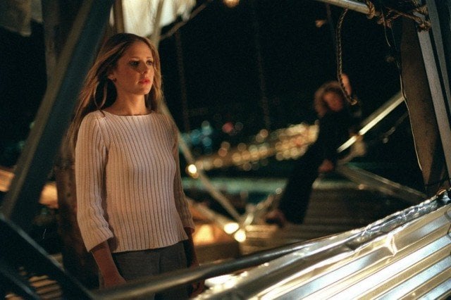 Sarah Michelle Gellar as Buffy Summers on Buffy the Vampire Slayer in a white sweater on a steel structure