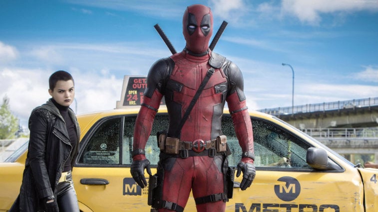 Ryan Reynolds as 'Deadpool' in front of a car. 