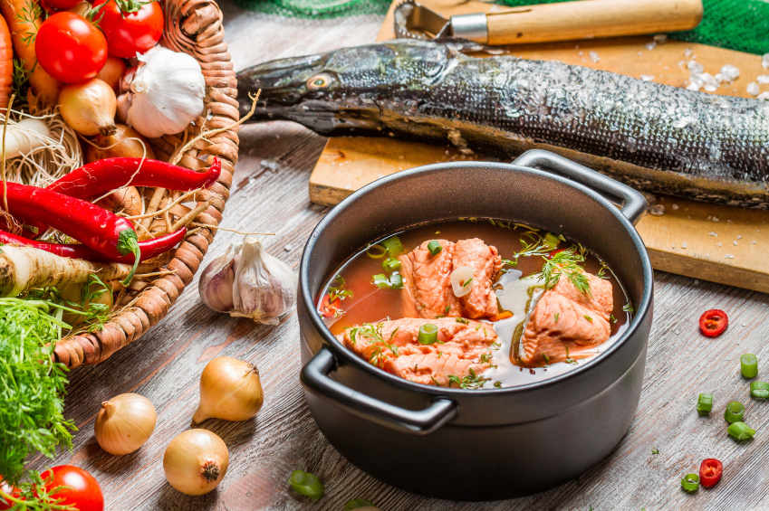 making spicy fish soup with chiles and fresh fish in a heavy pot