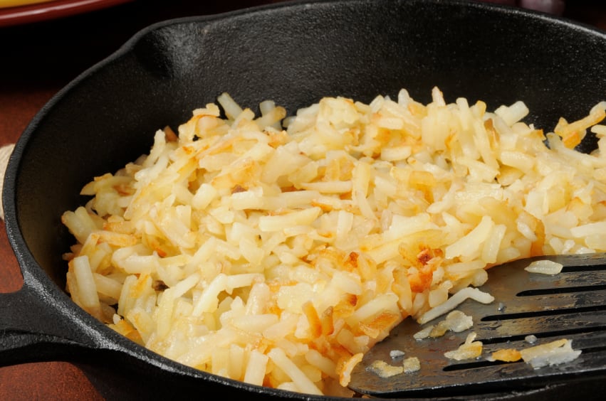 close-up of hash browns cooking in a cast-iron skillet