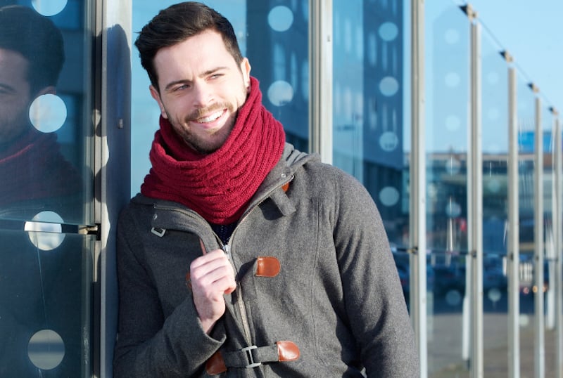 Smiling man with jacket and scarf relaxing outdoors