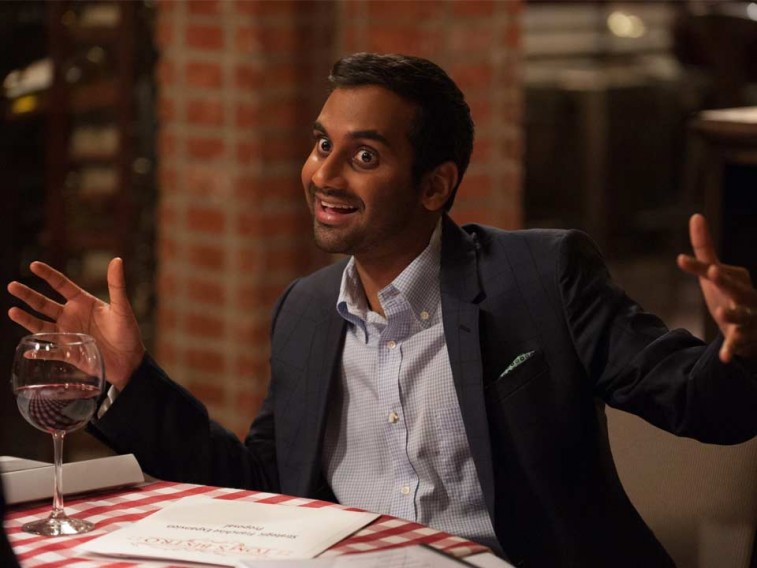 Aziz Ansari sits in a restaurant at a table with a glass of wine in Master of None