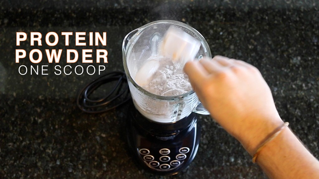 adding a scoop of protein powder to a blender for a protein shake