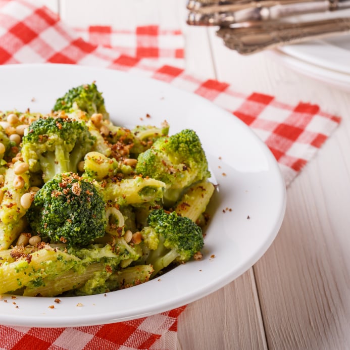 bowl of broccoli pasta with a checkered palcemat