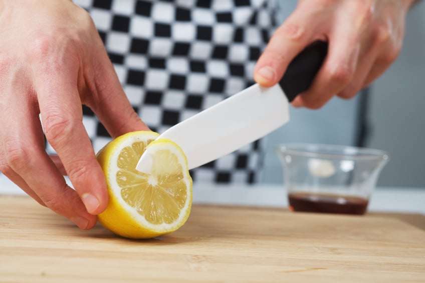 thinly slicing a lemon on a cutting board