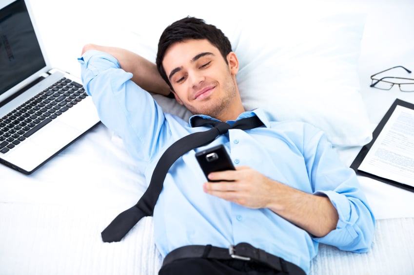 young business man lying and using smartphone