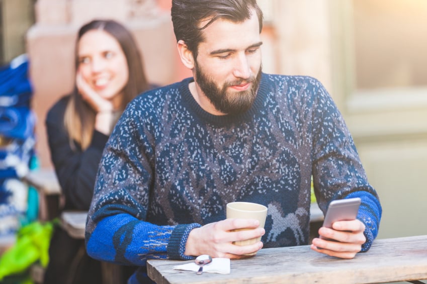 man using smartphone in a cafe