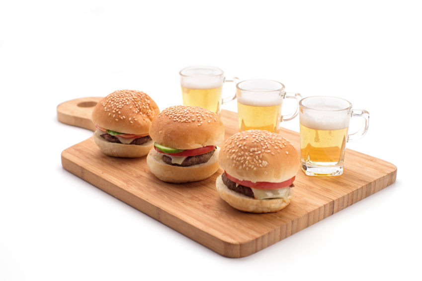 three burgers and beers on wooden board