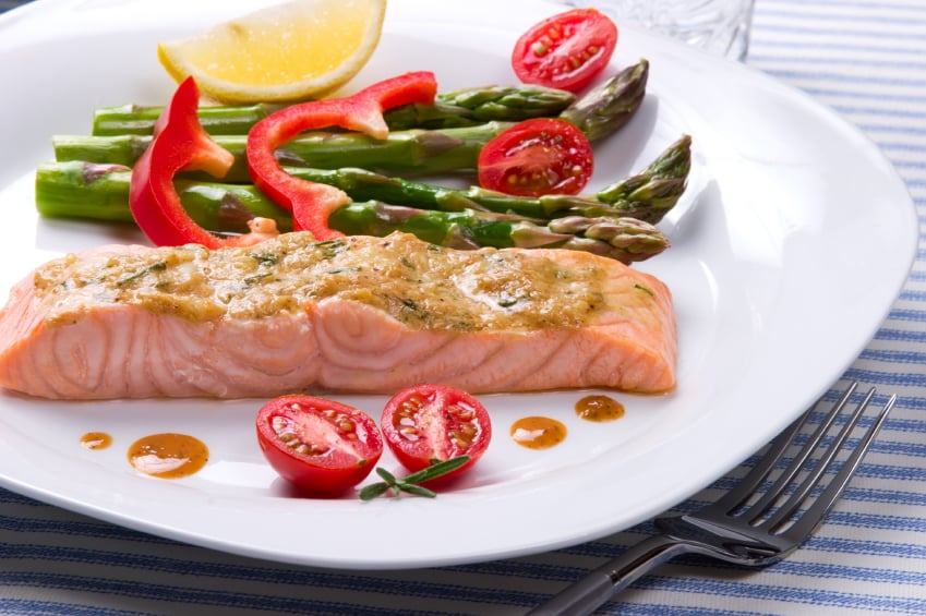 salon with a mustard and herb topping served with peppers, tomatoes, and asparagus