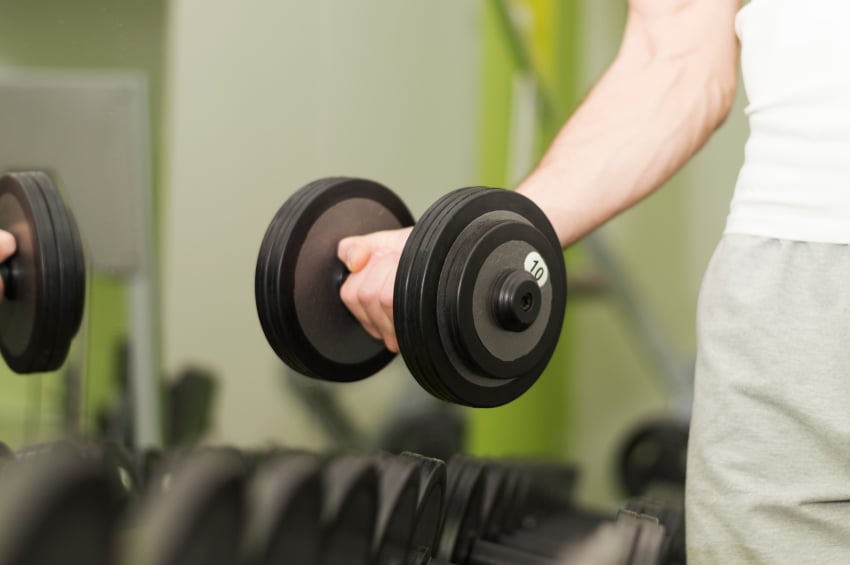 man picks up a dumbbell from a rack