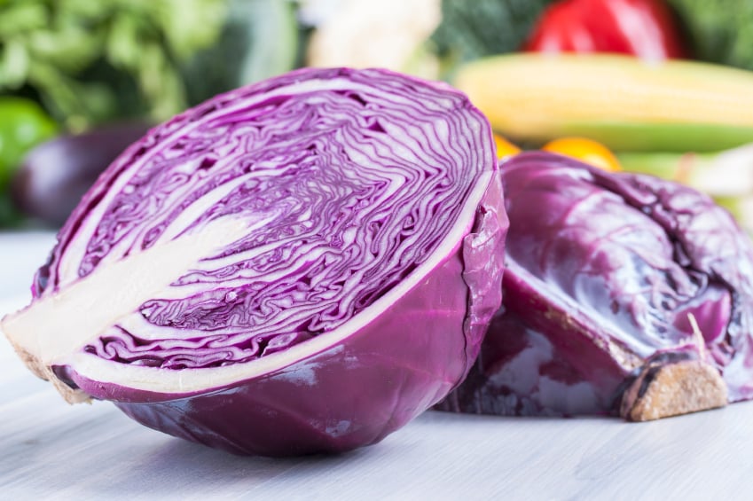 head of red cabbage cut in half on a cutting board