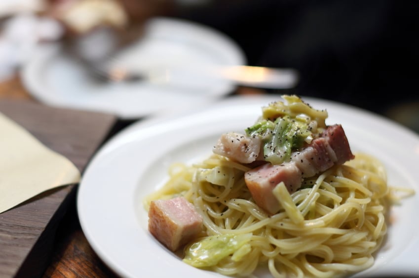 close shot of a plate of pasta with bacon and cabbage