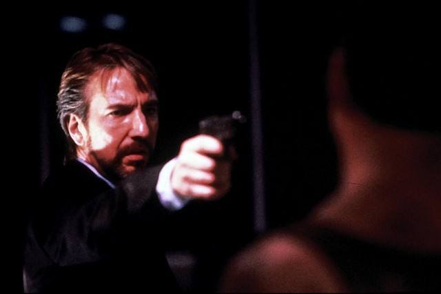 Hans Gruber is pointing a gun at John McClane.