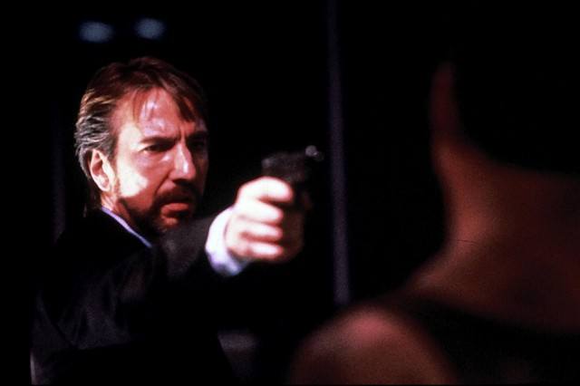 Hans Gruber is pointing a gun at John McClane.