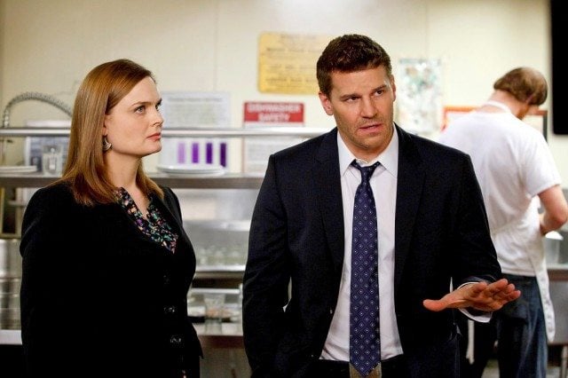 Emily Deschanel and David Boreanaz stand next to each other in a kitchen in Bones