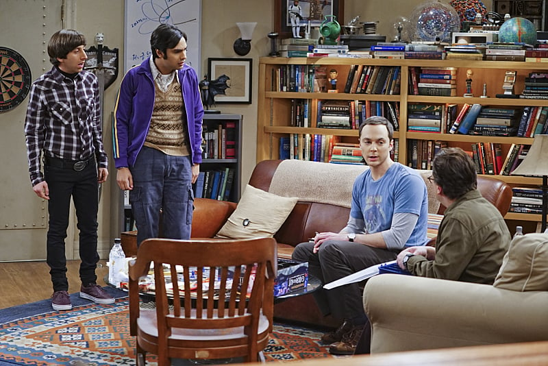 The men of the Big Bang Theory sit and stand in a living room