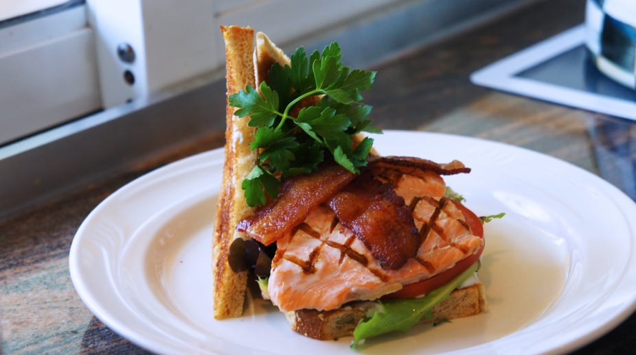 hearty grilled salmon sandwich with lettuce, tomato, and bacon