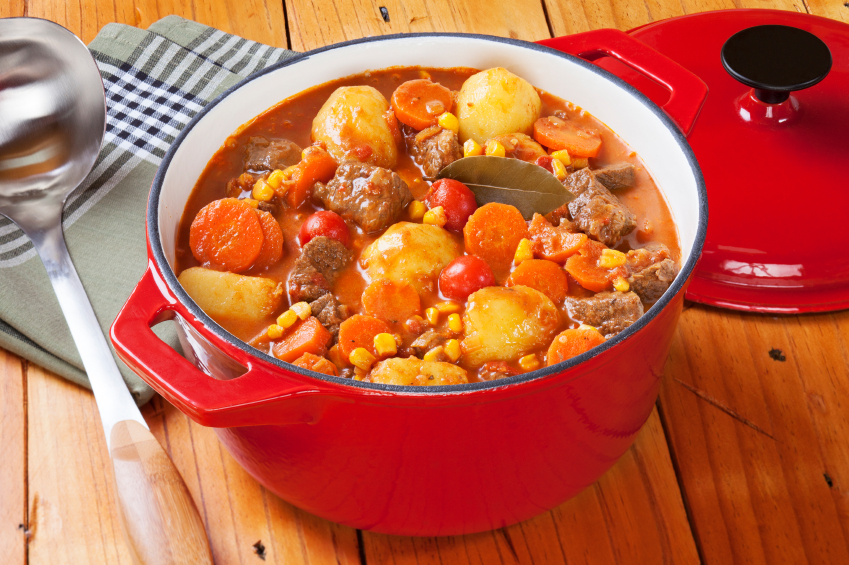 beef stew with carrots, potatoes, an corn in a red pot