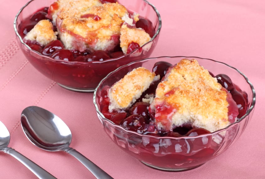 two bowls filled with cherry cobbler that has a biscuit topping