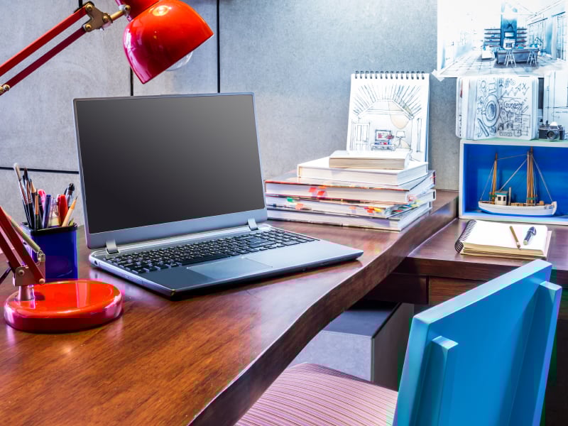 a laptop on a desk and with pen holder and table lamp