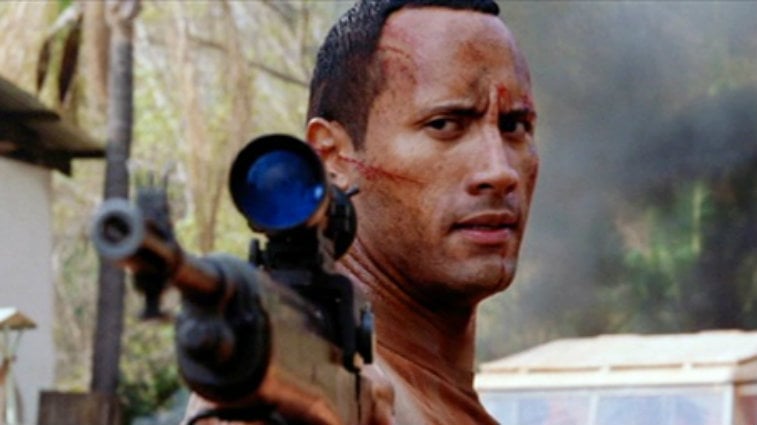 This is a closeup of Dwayne Johnson bloody and holding a gun in The Rundown.