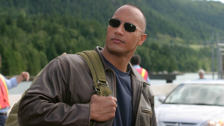 Dwayne Johnson is wearing sunglasses and has on a backpack in Walking Tall.