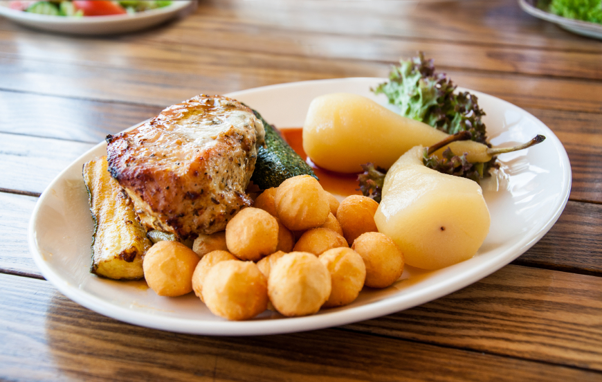 plate of roasted pork and pears on a wooden table