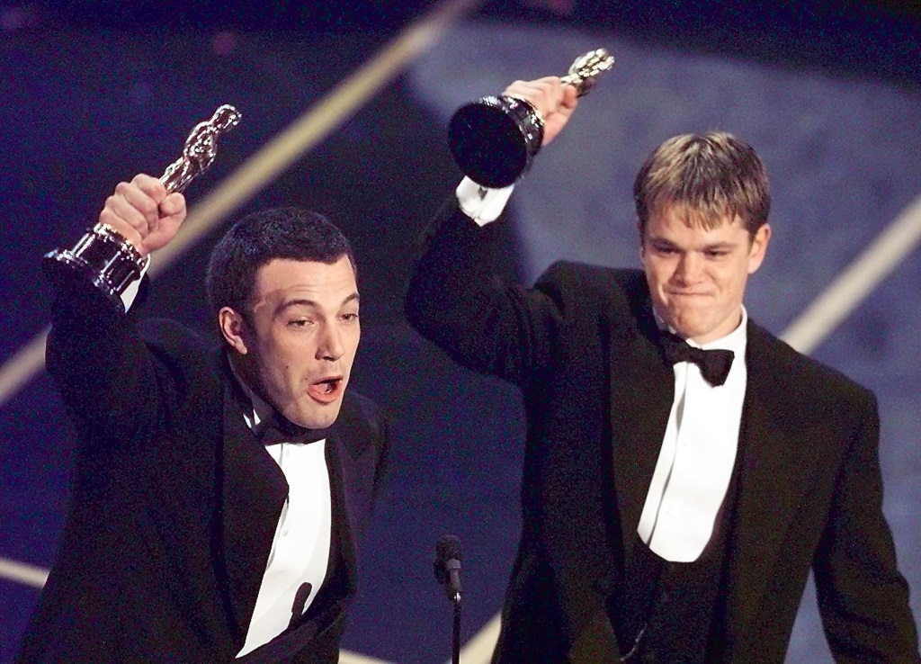 Matt Damon and Ben Affleck at the Oscars holding up their awards.