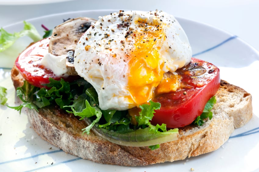open face sandwich on rustic toast with eggs, tomatoes, and lettuce