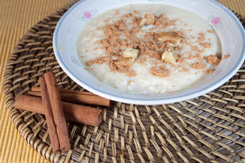 bowl of rice pudding topped with brown sugar, cinnamon, and walnuts