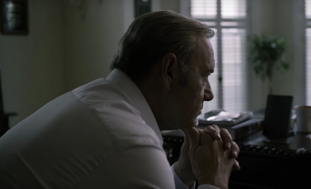 Frank leans his chin in his hands in House of Cards