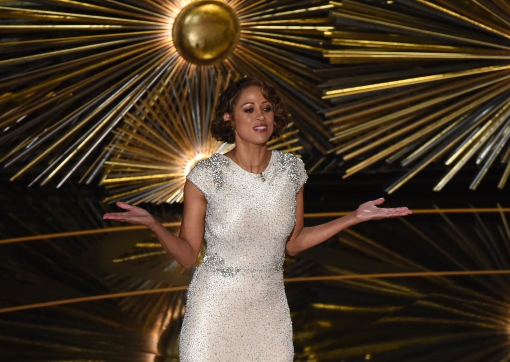 Stacey Dash with her hands out, wearing a white dress