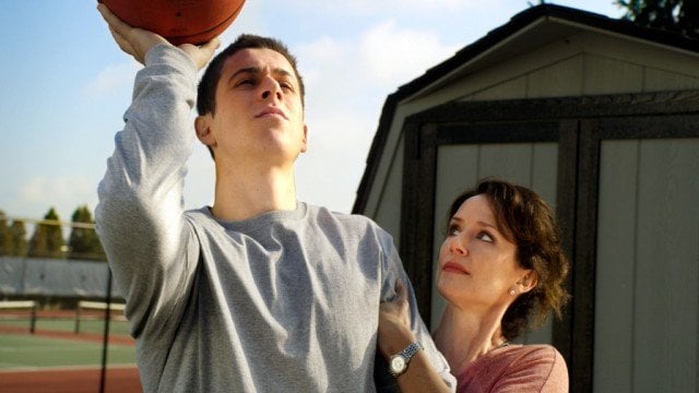 Man throwing basketball and woman holding onto him