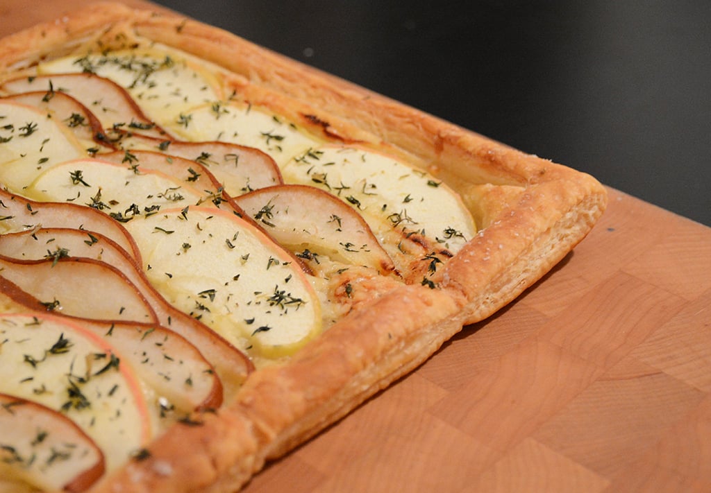 cheddar, apple, and pear tart on a wooden cutting board