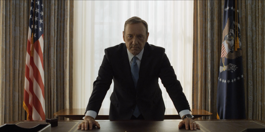 Frank Underwood leaning over the desk in the Oval Office, looking directly at the camera